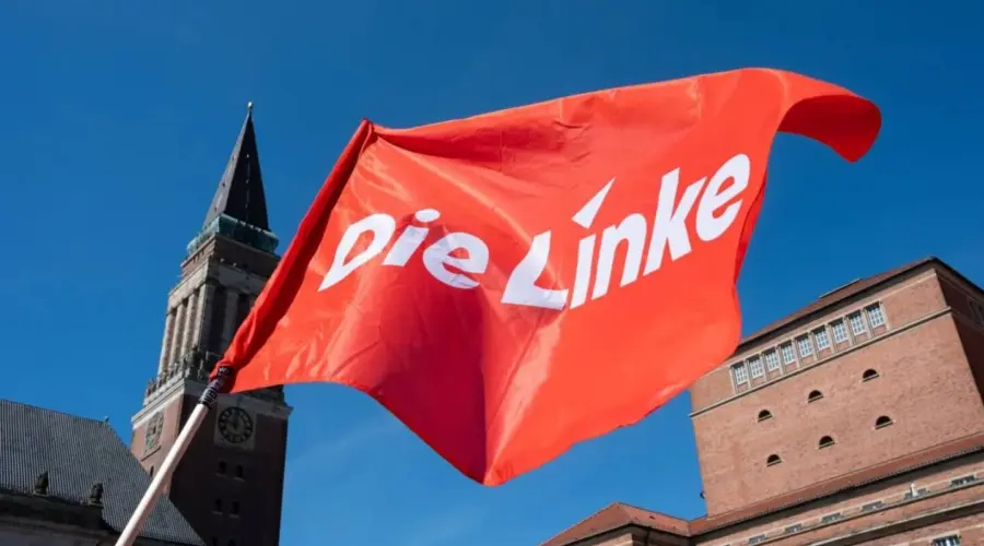 Rote Fahne mit Die Linke-Logo vor dem Kieler Rathausturm.
