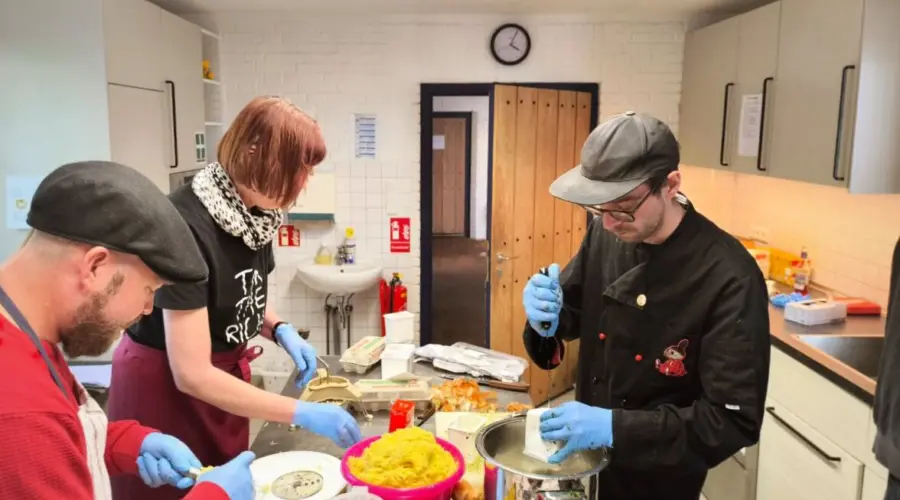 Ein Team der Linken Kiel, darunter Björn Thoroe, bei der Zubereitung von Kartoffelpuffern in einer großen Küche.