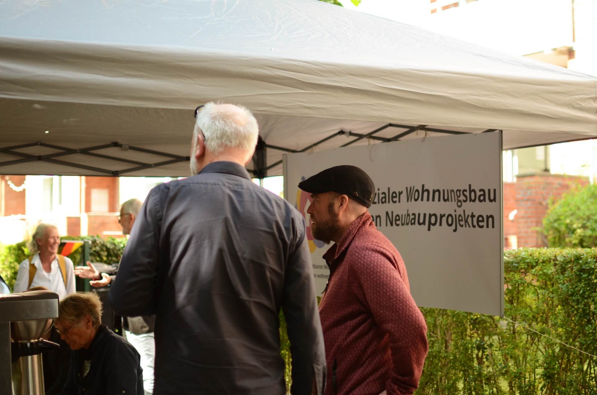 Björn Thoroe im Gespräch während des Straßenfestes in der Lornsenstraße am 7. September 2025. Im Hintergrund ein Banner des "Bündnis für bezahlbaren Wohnraum", auf dem folgendes steht: Sozialer Wohnungsbau bei allen Neubauprojekten!