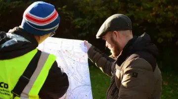 Björn Thoroe und Niklas Hielscher gucken auf eine Karte der geplanten Autobahn.