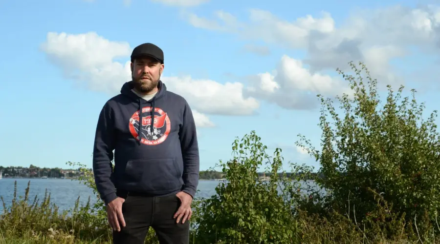 Porträt von Björn Thoroe. Im Hintergrund grüne Büsche und die Kieler Förde.