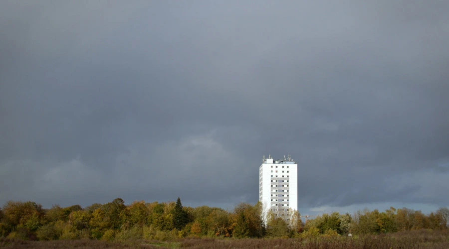 Aufnahme des Prüner Schlag vor der Zerstörung. Vor dunklen Wolken zeichnet sich das weiße Hochhaus ab.