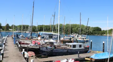 Hausboote und Beiboote an einem Steg im Kieler Plüschowhafen.