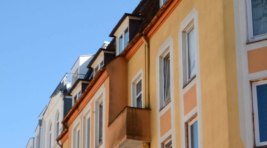 Zu sehen sind Fassade, Fenster und Balkone eines augenscheinlich sehr sanierungsbedürftigen Mehrfamilienhauses.