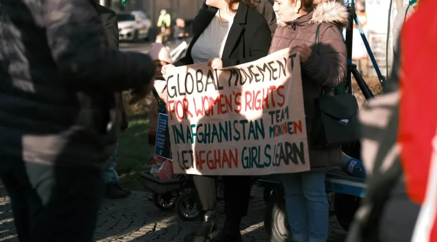 Bei einer Protestveranstaltung halten zwei Frauen ein Transparent mit folgender Aufschrift: "Global Movement for Women's Rights in Afghanistan – Let Afghan Girls Learn"