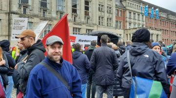 Björn Thoroe steht zusammen mit Streikenden der Gewerkschaft Verdi auf dem Rathausmarkt in Kiel.