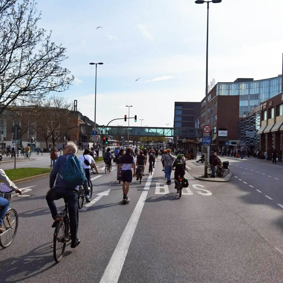 Demonstrierende auf Fahrrädern in der Straße Sophienblatt in Kiel. Im Hintergrund ist der Kieler Hauptbahnhof zu sehen.
