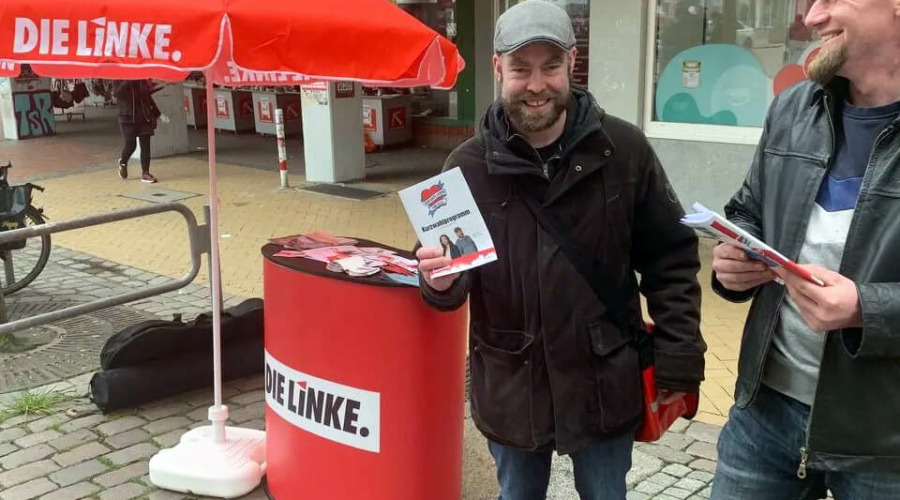 Björn Thoroe und eine weitere Person vor einem Infostand der Partei DIE LINKE in Gaarden.