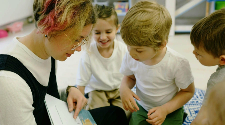 Eine Erzieherin liest Kindergarten-Kindern vor.