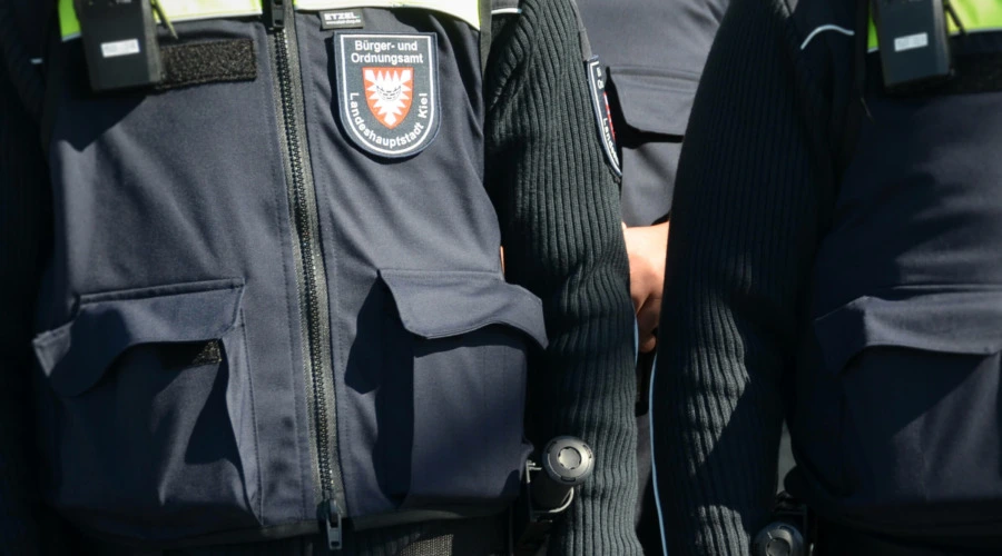 Zu sehen sind Uniformen mit der Aufschrift "Bürger- und Ordnungsamt Landeshauptstadt Kiel", am Gürtel Teleskop-Schlagstöcke.
