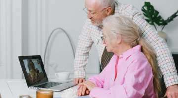 Ein älteres Paar ist per Video-Anruf auf einem Laptop im Gespräch mit einer jüngeren Frau.