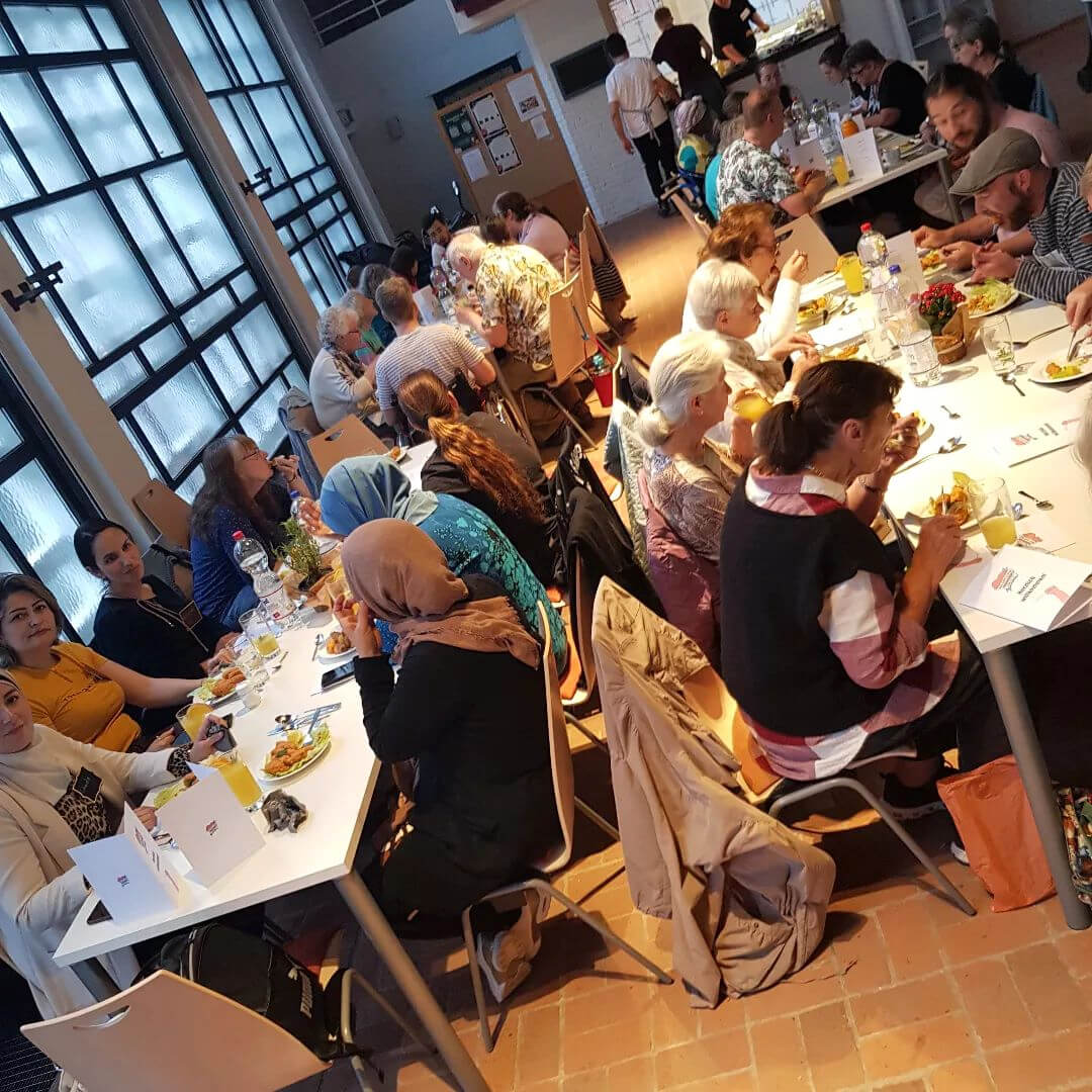 Zahlreiche Personen genießen in der Sozialkirche Gaarden die zubereiteten Mahlzeiten, darunter Björn Thoroe, der seine berühmte Müze trägt.