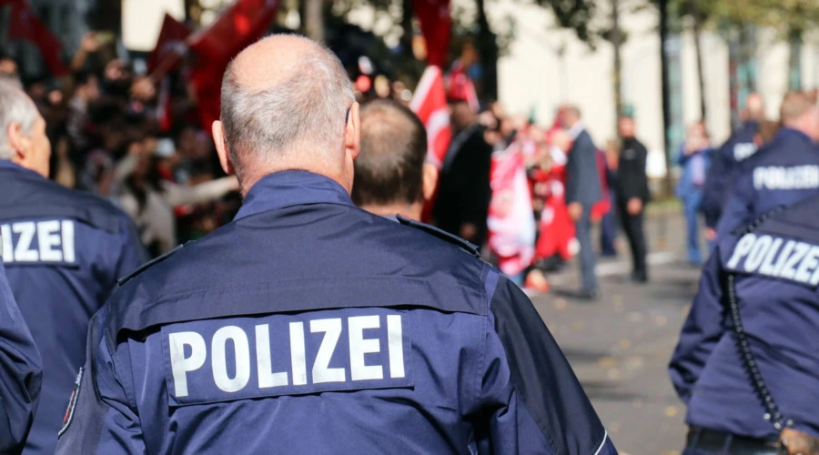 Ansicht von hinten: Polizisten gehen auf eine Demonstration zu. Der Schriftzug "Polizei" ist deutlich zu erkennen.