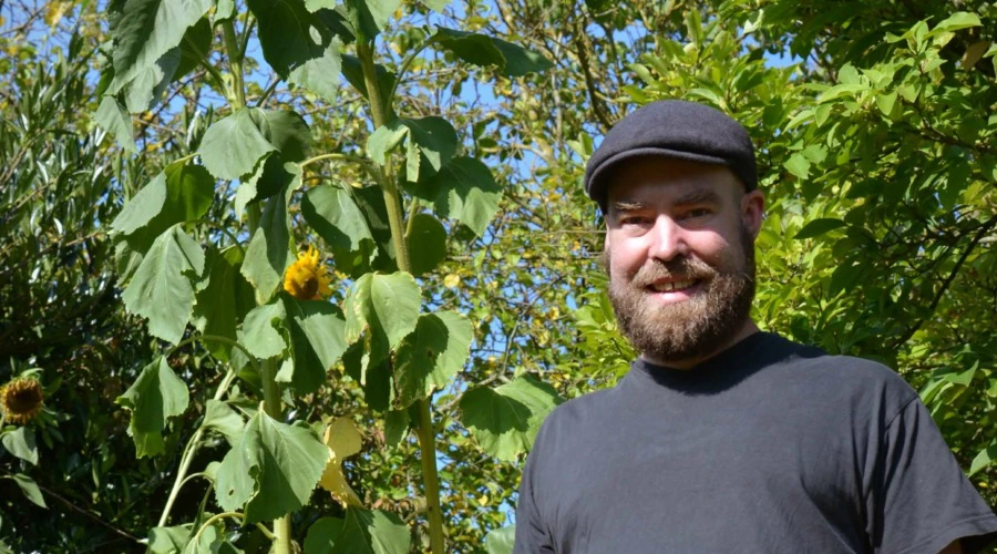 Im Vordergrund Björn Thoroe, im Hintergrund große Sonnenblumen.