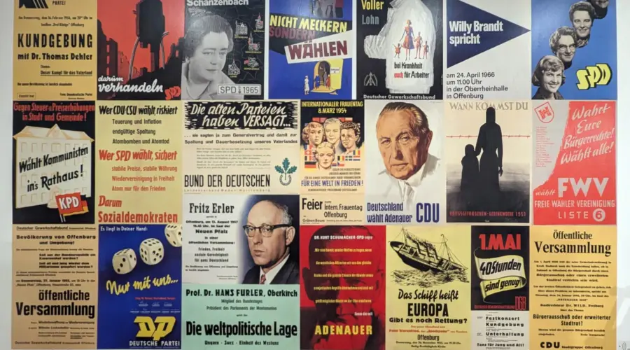 Zu sehen sind zahlreiche Wahlplakate aus den 1950er Jahren an einer Wand.