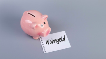 Ein Sparschwein steht vor einem Zettel, auf dem "Wohngeld" steht.
